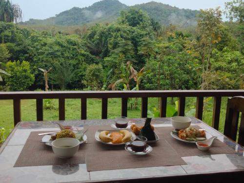 Una mesa con platos de comida en un balcón con vistas. en Sabai House Bungalow, en Ko Yao Noi