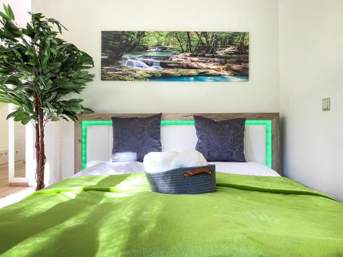 Un dormitorio con una cama verde con una pintura en la pared en Wohlfühl-Apartment mit kostenfreier Tiefgarage, WiFi und Kaffee, en Leipzig