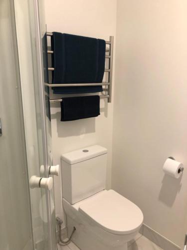 a bathroom with a toilet and two towels on a rack at Cozy Brand New Townhouse 35 in Auckland