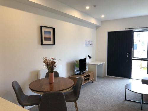 a living room with a table and a tv at Cozy Brand New Townhouse 35 in Auckland