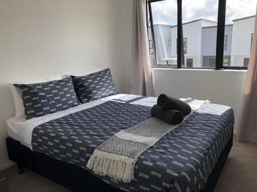 a bed with a black hat sitting on top of it at Cozy Brand New Townhouse 35 in Auckland