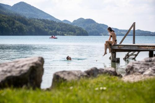 a woman sitting on a dock in a lake at Rennrad- & Triathlonhotel Jakob in Fuschl am See
