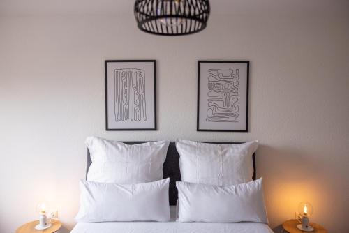 sypialnia z białymi poduszkami i dwoma obrazami na ścianie w obiekcie Modernes und Zentralgelegenes Apartment mit Küche, Netflix, und Balkon w mieście Duisburg