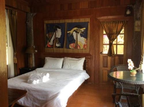 een slaapkamer met een bed met witte lakens en een tafel bij Himawari Restaurant & Cottage in Ban Nong Hin
