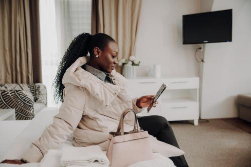 a woman sitting on a couch looking at a cell phone at Hotel Dolce International in Skopje