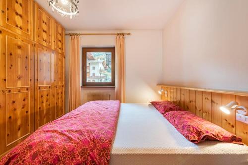a bedroom with a large bed with red blankets at Delizioso appartamento trilocale a Moena in Moena