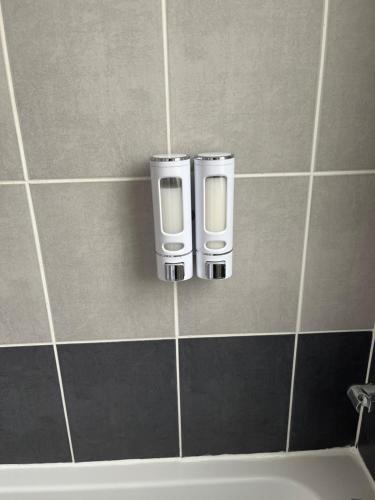 a bathroom with two soap dispensers on a tiled wall at Dam&HelMalo - 150m de la plus belle plage du Nord. in Dunkerque