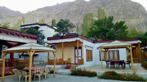 a restaurant with tables and umbrellas in front of a building at Chamba resort in Leh