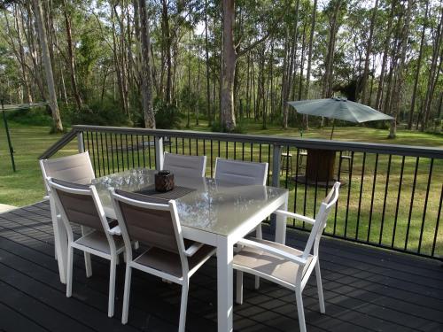 a white table and chairs on a deck with an umbrella at Bronte Lodge, Wine Country Stay Hunter Valley with Games Room, Close to Town in Greta Main
