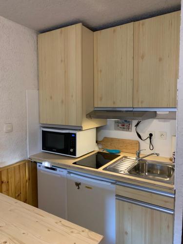 La cuisine est équipée de placards en bois, d'un évier et d'un four micro-ondes. dans l'établissement Appartement vue montagne avec wifi, à Saint-Lary-Soulan