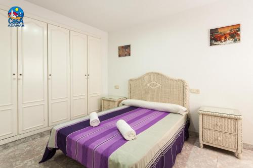 - une chambre avec un lit, une couverture violette et une chaise dans l'établissement Residencial Casablanca Casa Azahar, à Alcossebre