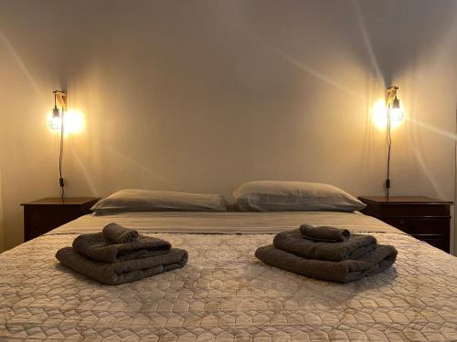 1 cama con 2 toallas y 2 lámparas en LHE Beating Heart Casa Tiziana, en Cesena