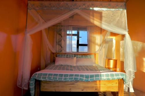 ein Schlafzimmer mit einem Himmelbett und einem Fenster in der Unterkunft The Red House in Amboseli-Nationalpark