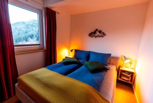 a bedroom with a bed with blue sheets and a window at Panorama Apartment Bauernhof Mandl in Murau