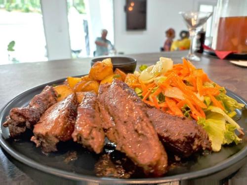 un plato de comida con carne y verduras en una mesa en 2 0 HÔTEL Ylang, en Labattoir