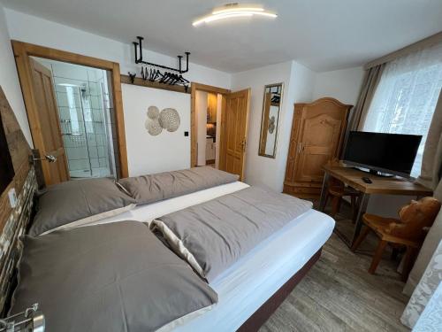 a large bed in a room with a desk and a television at Haus Eder Steiner in Saalbach Hinterglemm