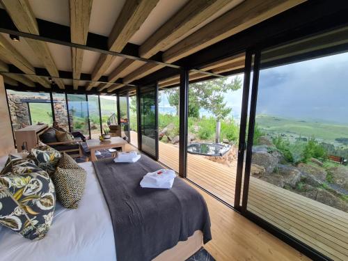a bedroom with a large bed and large glass windows at Eagle View on Beumont in Dullstroom