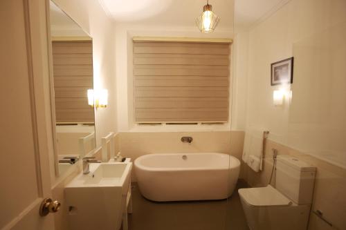 a bathroom with a tub and a toilet and a sink at The Estate 1920 in Pelmadulla