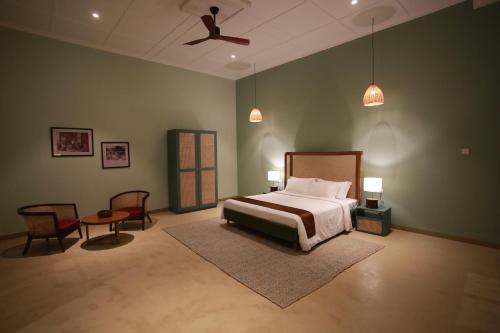 - une chambre avec un lit, deux chaises et un ventilateur de plafond dans l'établissement The Estate 1920, à Pelmadulla