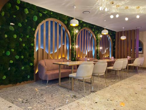 een restaurant met tafels en stoelen en een groene muur bij Gloria Suite Hotel in Trabzon
