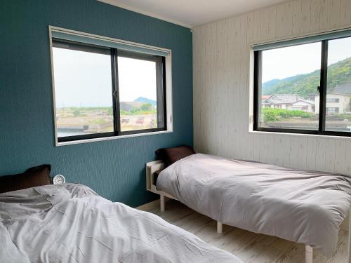 1 dormitorio con 2 camas y 2 ventanas en Pier39 Uchiumi Cozy house located in front of the sea and harbor! en Miyazaki