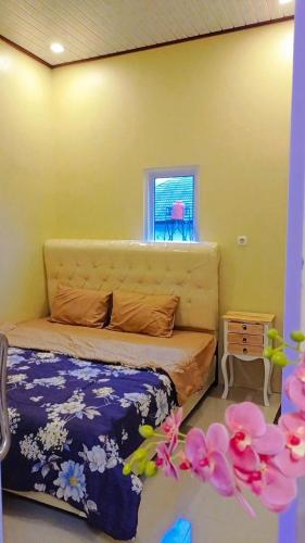 a bedroom with a bed and a window and flowers at Villa atas awan in Wonosobo