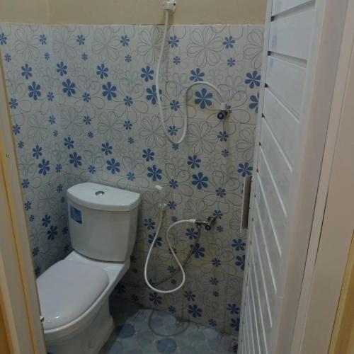 a bathroom with a toilet and blue and white tiles at Villa atas awan in Wonosobo