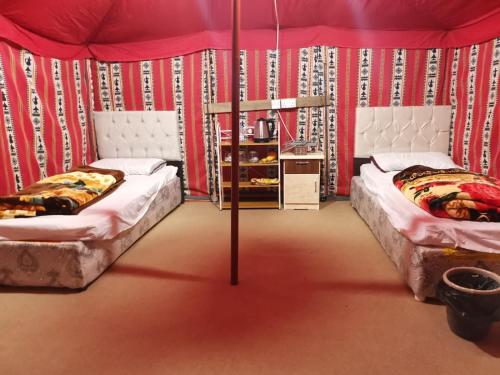 2 Betten in einem Zimmer mit roten Wänden in der Unterkunft Almazham camp resort in Al-'Ula