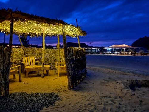 Almazham camp resort في العلا: طاولة وكراسي على الشاطئ في الليل