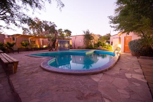 a swimming pool in a yard with a bench at Hotel-Camping Takha Takha in San Pedro de Atacama
