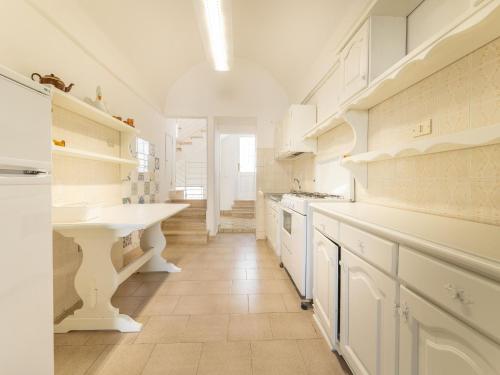 La cuisine est équipée de placards blancs et d'un évier blanc. dans l'établissement Spacious holiday home in Marina di Mancaversa with terrace, à Marina di Mancaversa
