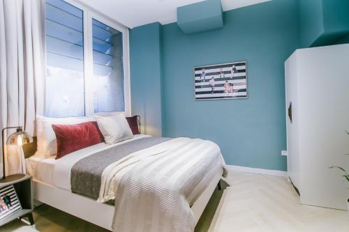 een slaapkamer met blauwe muren en een bed met een raam bij Monochrome Rothschild - Smart Hotel by Loginn Tel Aviv in Tel Aviv