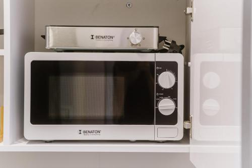 a microwave sitting on a shelf in a kitchen at Monochrome - an Autonomous Hotel by Loginn in Tel Aviv