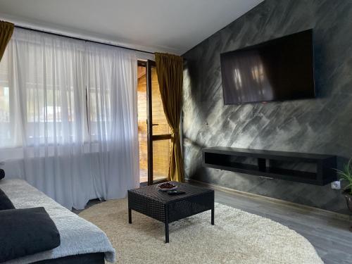 ein Wohnzimmer mit einem Sofa und einem TV an der Wand in der Unterkunft Alvi Apartment Poiana Brasov in Poiana Brașov