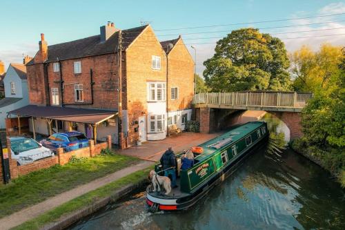 a boat traveling down a river with a dog on it at Hidden Gem Canal Facing Retreat with lovely walks in Hopwas