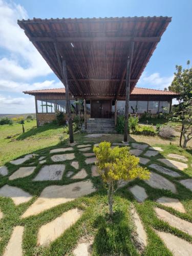 a building with a roof on top of a field at Pousada Mirante Serra Verde in Carrancas