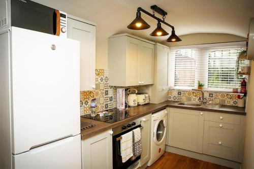 a kitchen with white cabinets and a white refrigerator at Hidden Gem Canal Facing Retreat with lovely walks in Hopwas
