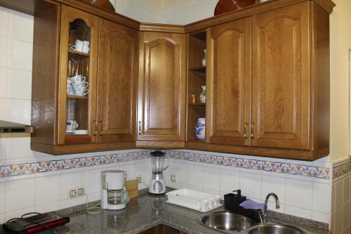 una cocina con armarios de madera y fregadero en La Escondida en Tornavacas