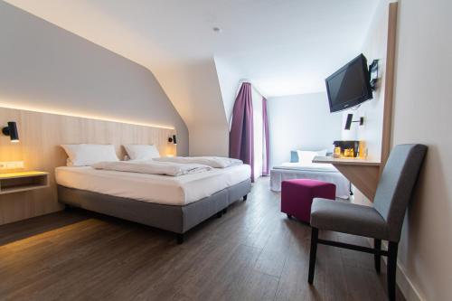 ホッケンハイムにあるTaste Hotel Hockenheimのベッドと椅子付きのホテルルーム
