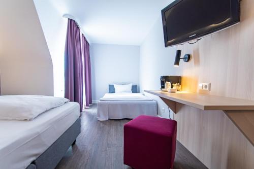 a hotel room with two beds and a flat screen tv at Taste Hotel Hockenheim in Hockenheim