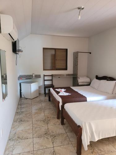 a hotel room with two beds and a table at Pousada Sol Nascente in Paraopeba