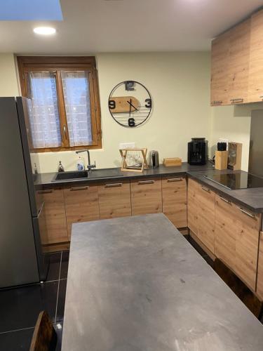 une cuisine avec une table et une horloge au mur dans l'établissement Au nid d'amour, à Bellencombre