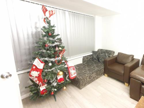 a christmas tree in a living room with a couch at Wetherne House, Beautiful Home, Parking Garden WiFi Self Check-in in Luton