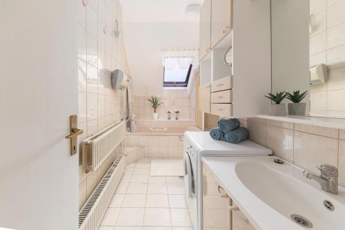 een witte badkamer met een wastafel en een bad bij Apartma Lea in Slovenj Gradec
