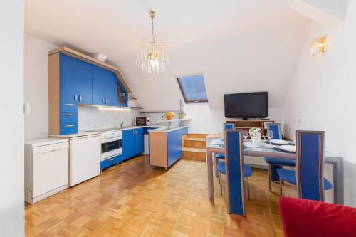 スロヴェニ・グラデツにあるApartma Leaのキッチン(青いキャビネット、テーブル、椅子付)