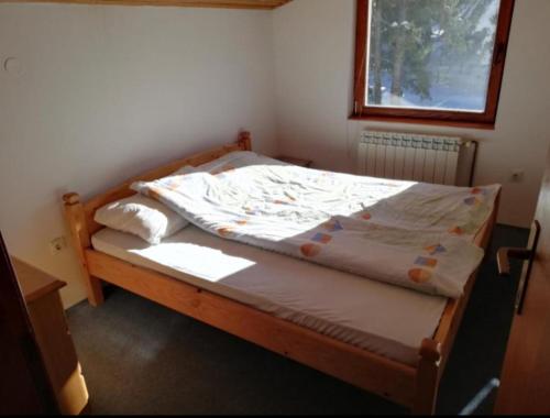 un letto di legno in una stanza con una finestra di Mountain Flower a Jahorina