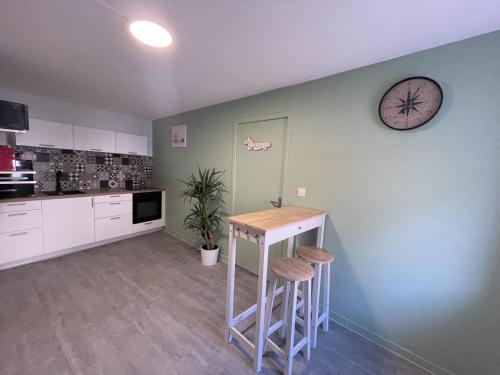 a kitchen with a table and a clock on the wall at Le Corbusier - Cosy & SPA in Firminy