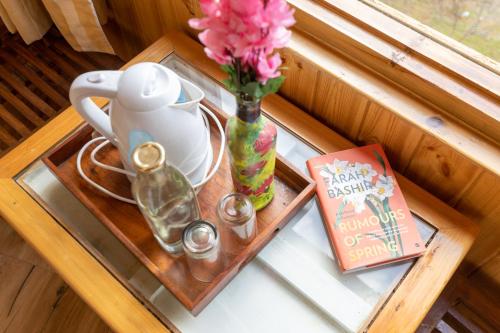 a tray with a vase of flowers and a book at Khwabeeda Stays in Jibhi