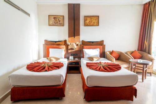 a hotel room with two beds and a couch at Aracan Eatabe Luxor Hotel in Luxor