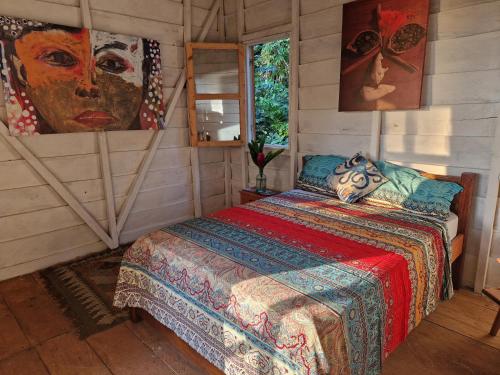 a bedroom with a bed and a painting on the wall at World's View Wild Camping Salaszoi, Principe Island in Santo António